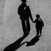 Mother and child on an open road, photographed from behind.